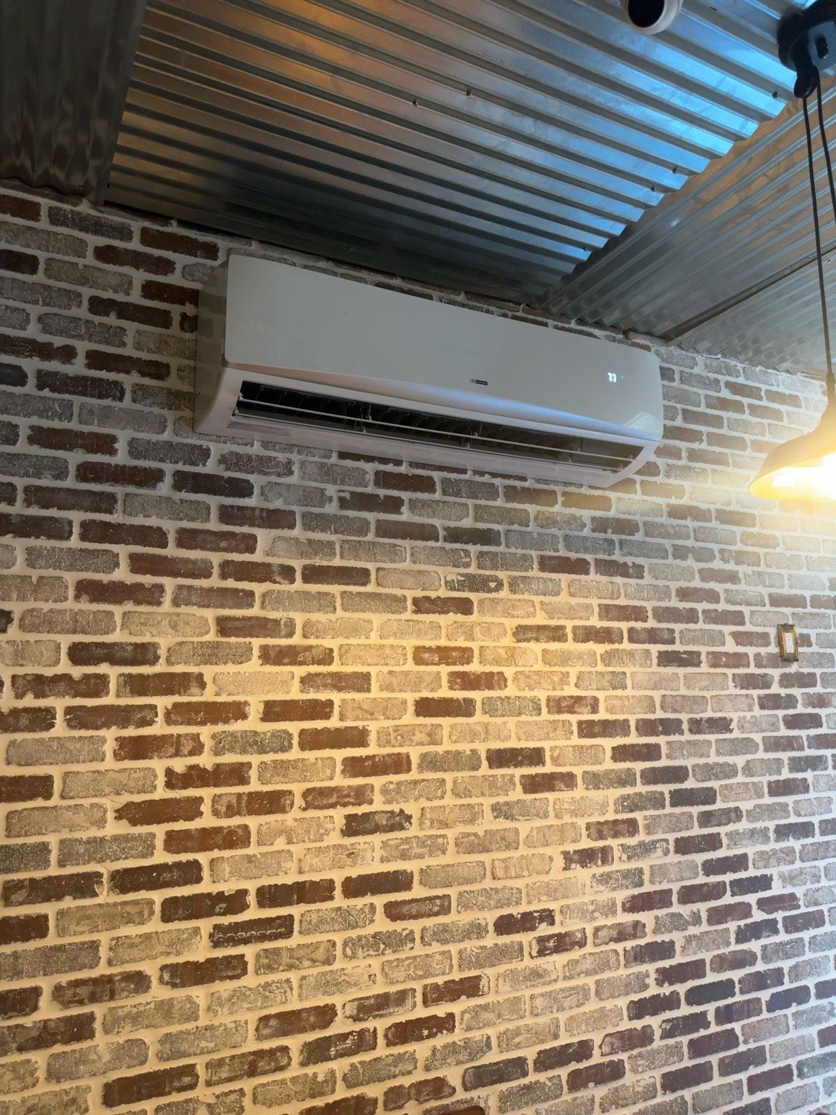Ductless mini-split head mounted on a brick wall