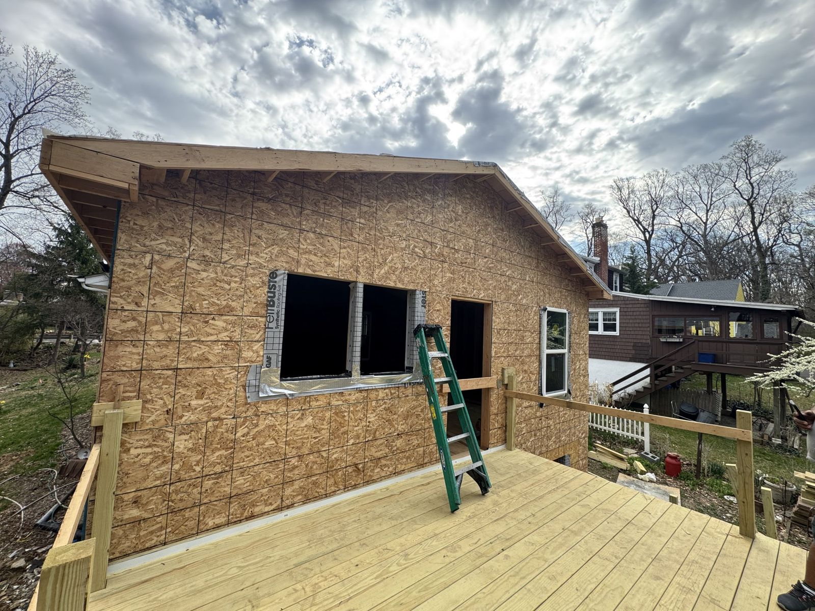 Rear home addition framed and sheathed, with a new deck in front