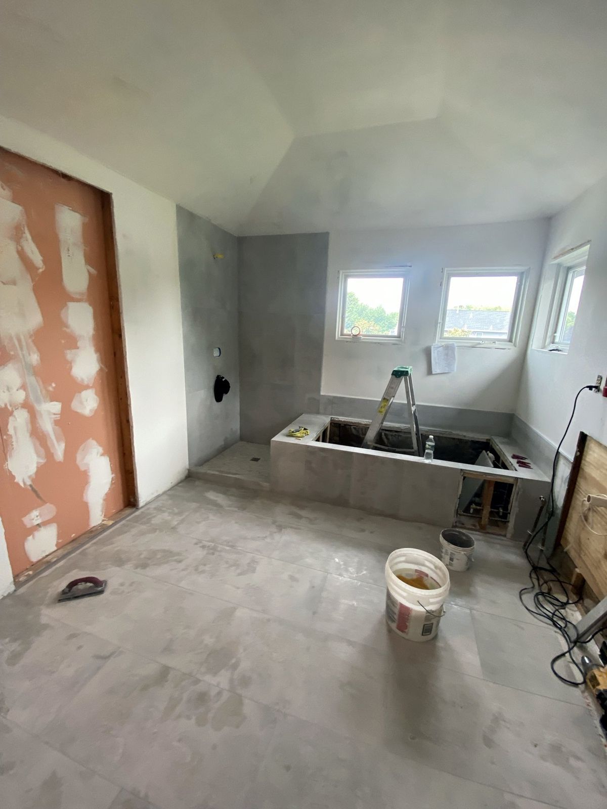 Same bathroom with large-format wall and floor tile set, tiled tub deck and a mosaic shower floor