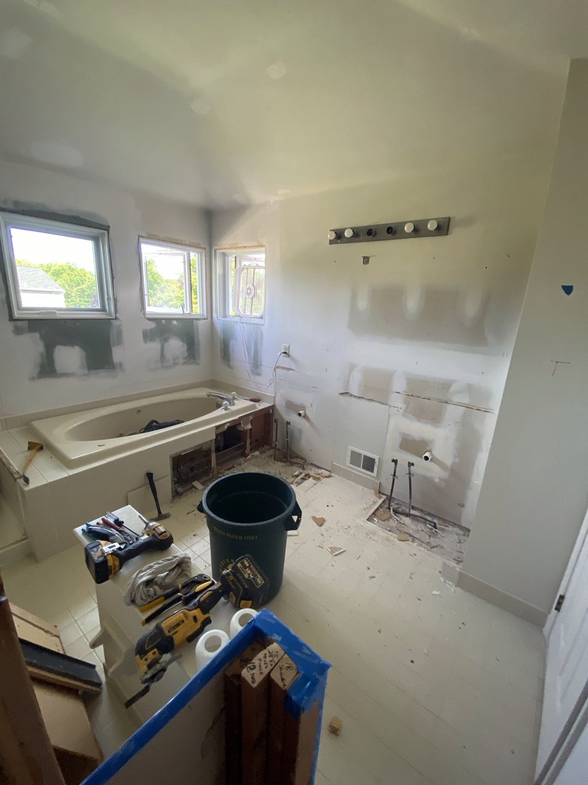 Primary bathroom before the remodel: old tub deck torn open, vanity removed and floor tile coming up
