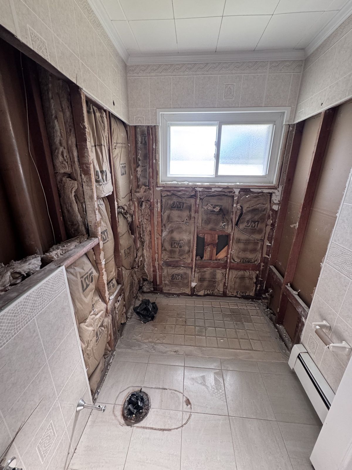 Bathroom gutted to the studs, old tile still on the floor