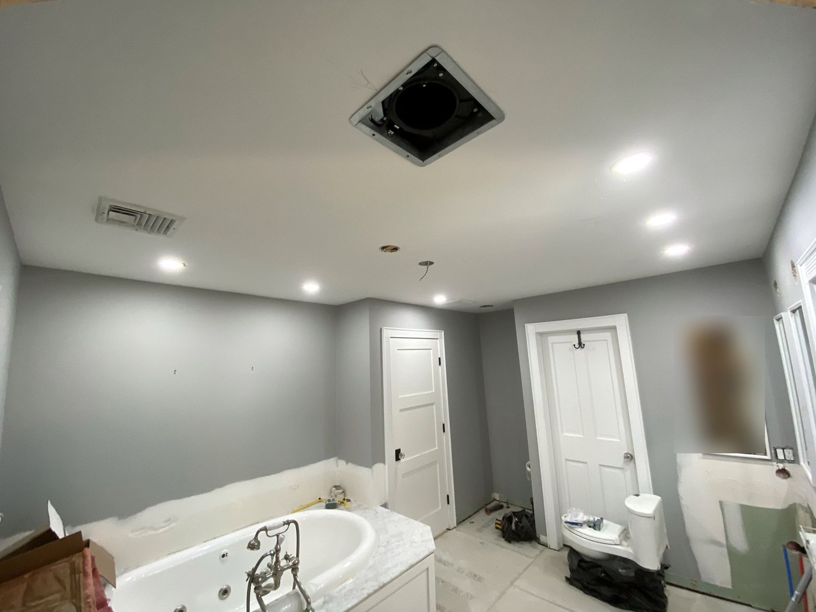 Primary bathroom mid-remodel: walls painted, recessed lights in, whirlpool tub set and floor protected