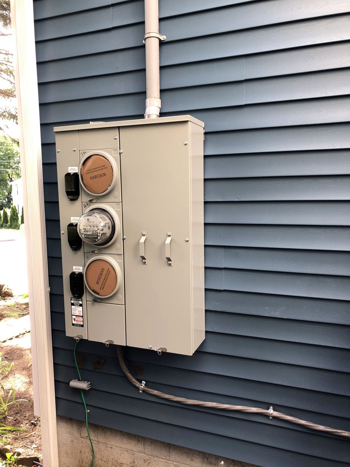 New three-meter unit with service disconnects mounted on the siding, grounding conductor bonded