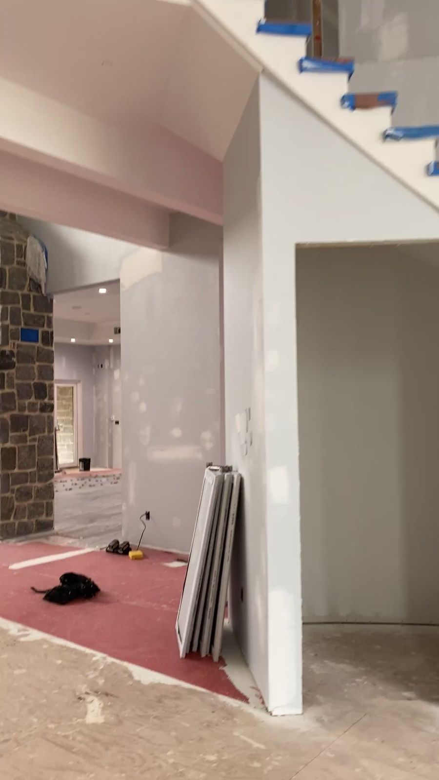 Inside a new home at the drywall stage: two-story living area and staircase