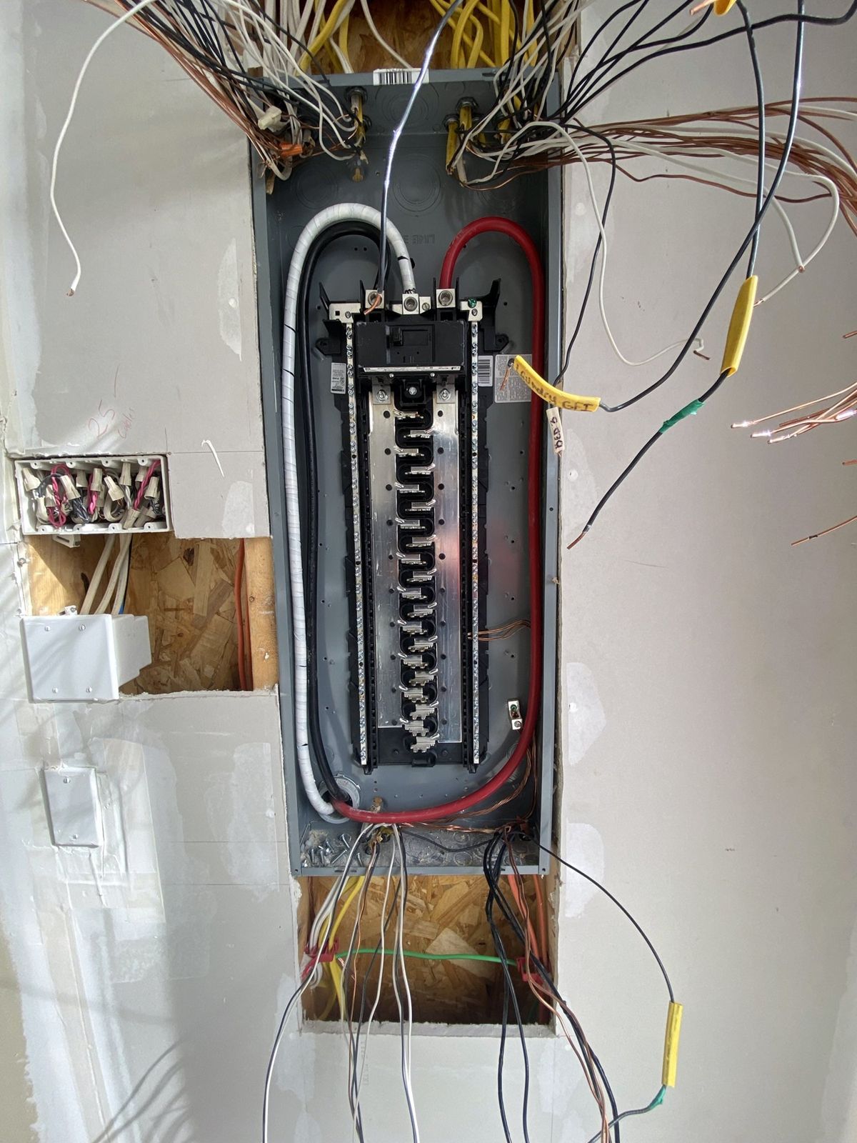 New main breaker panel set in the wall, home-run cables pulled in from above and below