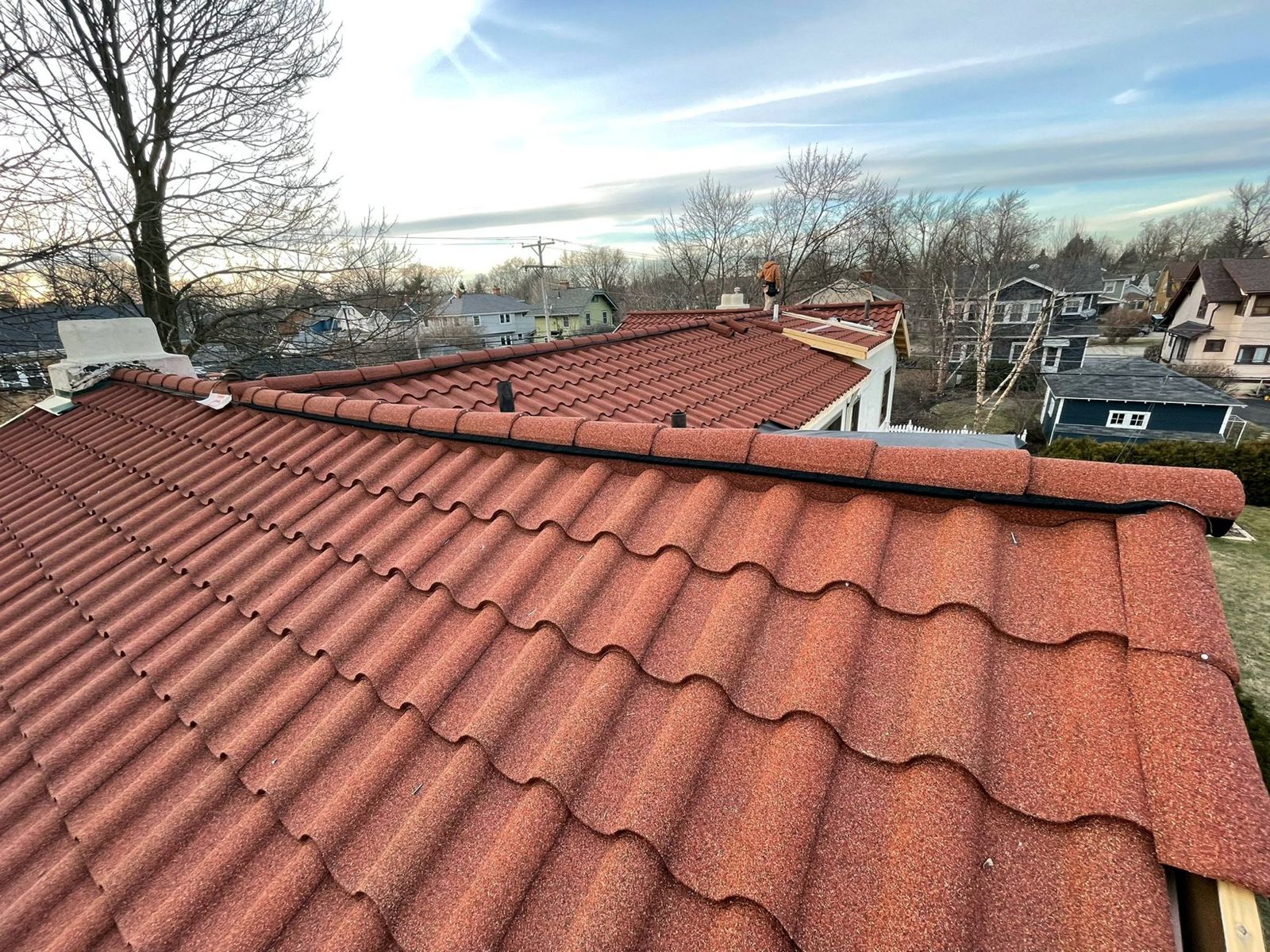 Stone-coated steel tile roof with new ridge caps on a two-level home